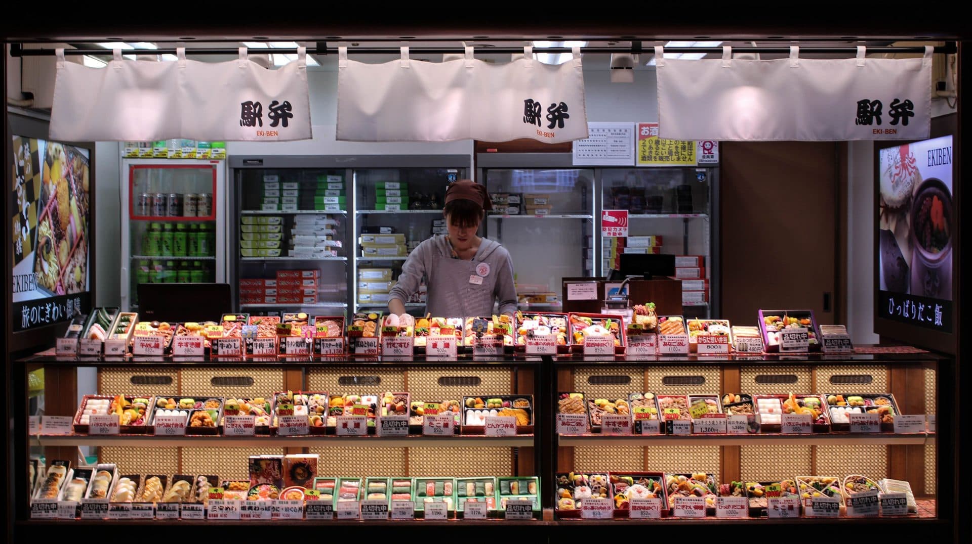 A woman arranging bento boxes at a department store food counter in Tokyo