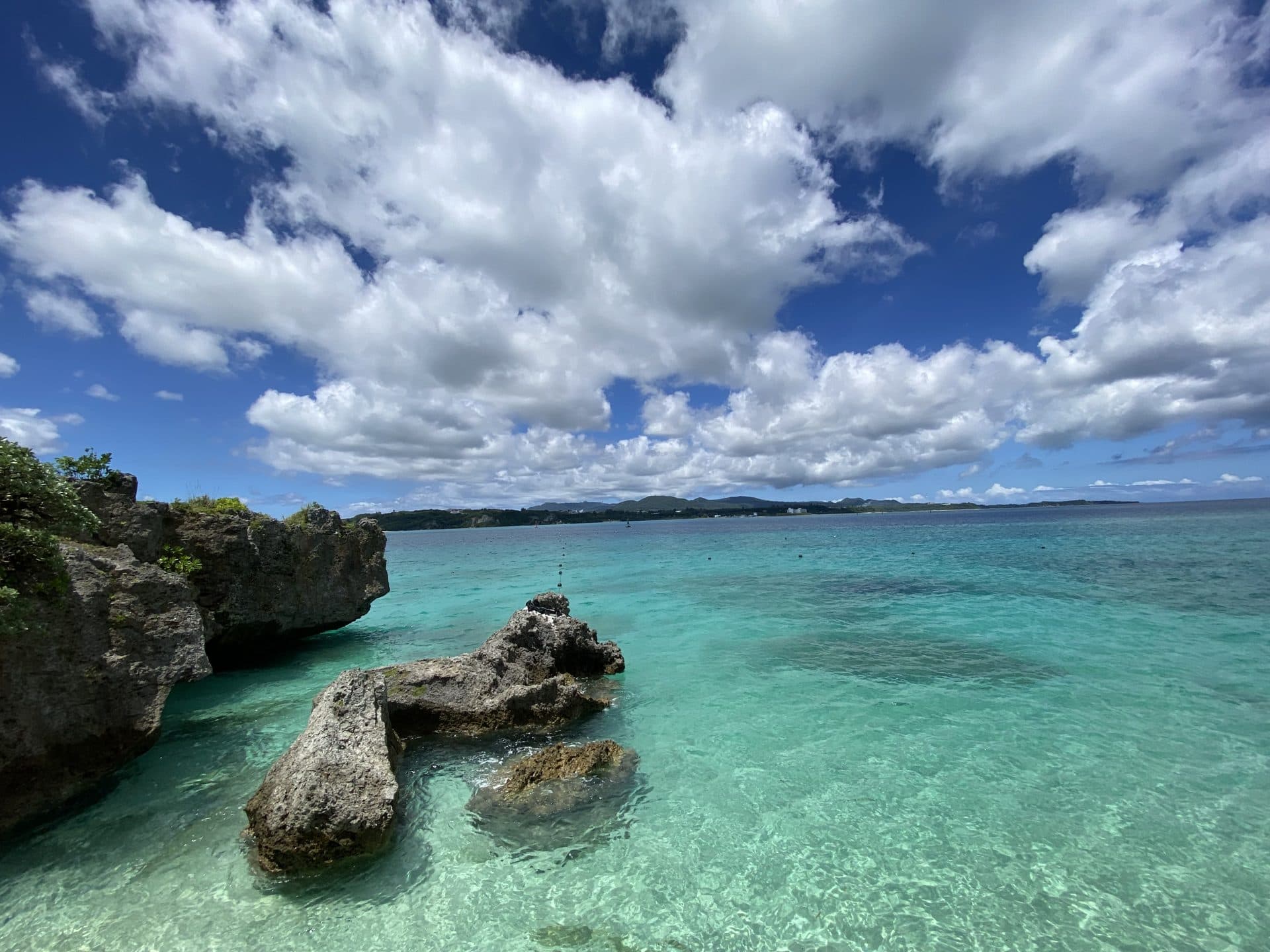 Turquoise water and coral rock formation off the coast of Okinawa under a bright summer sky