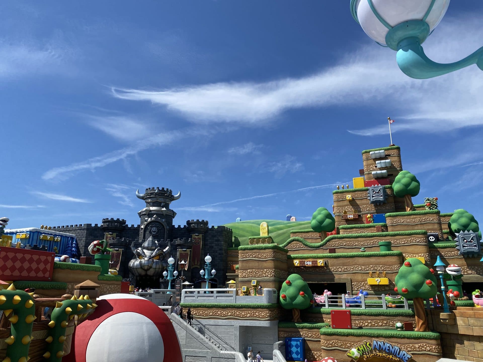 Super Nintendo World di Universal Studios Japan, dengan pipa warp hijau bertema Mario dan menara kastil di bawah langit biru