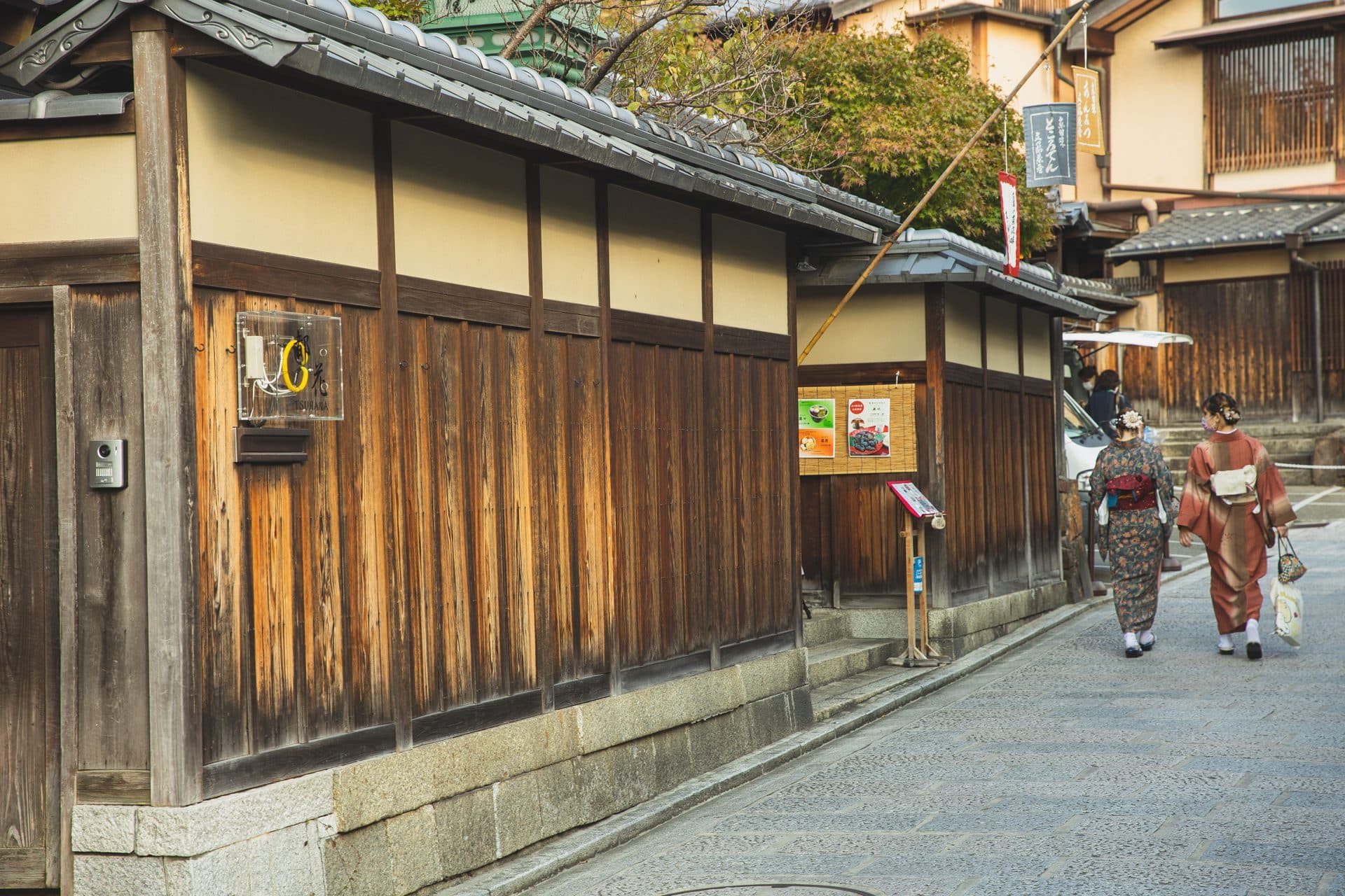 Anonymous ethnic women in kimonos walking along kyoto street