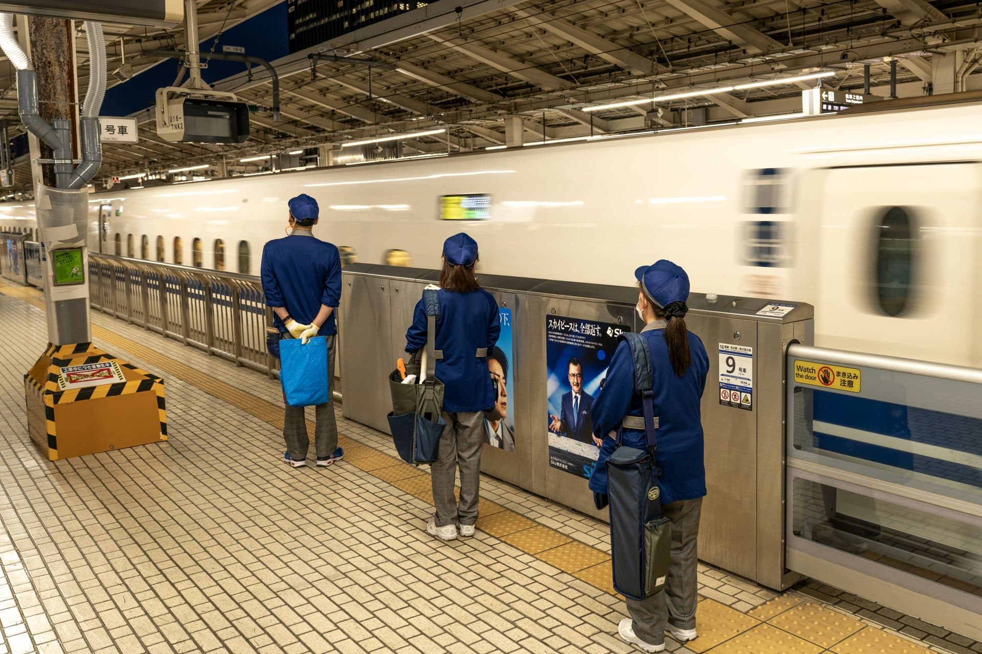 Bullet train speeding through a Japanese station with commuters