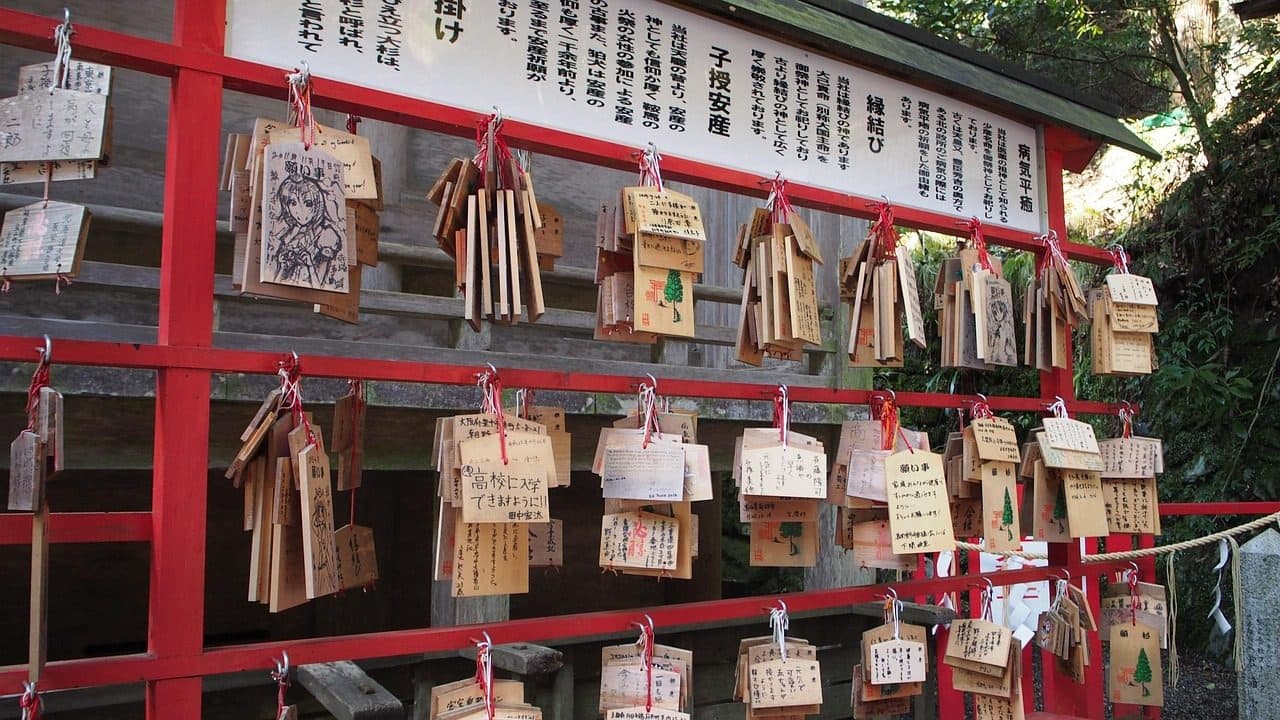 Wooden ema prayer plaques with handwritten wishes hanging on a red rack at Kifune Shrine in Kyoto