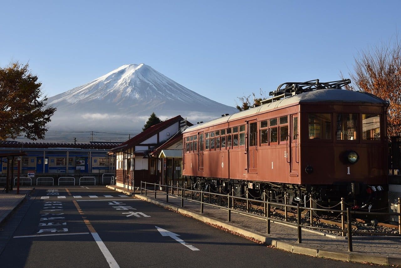 Snow-capped Mt Fuji behind Kawaguchiko Station, with a vintage brown railway carriage on display beside the station building
